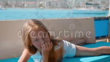 快乐的女孩躺在海上游艇上。 年轻的少女在海上漂流船上放松。 旅游女孩